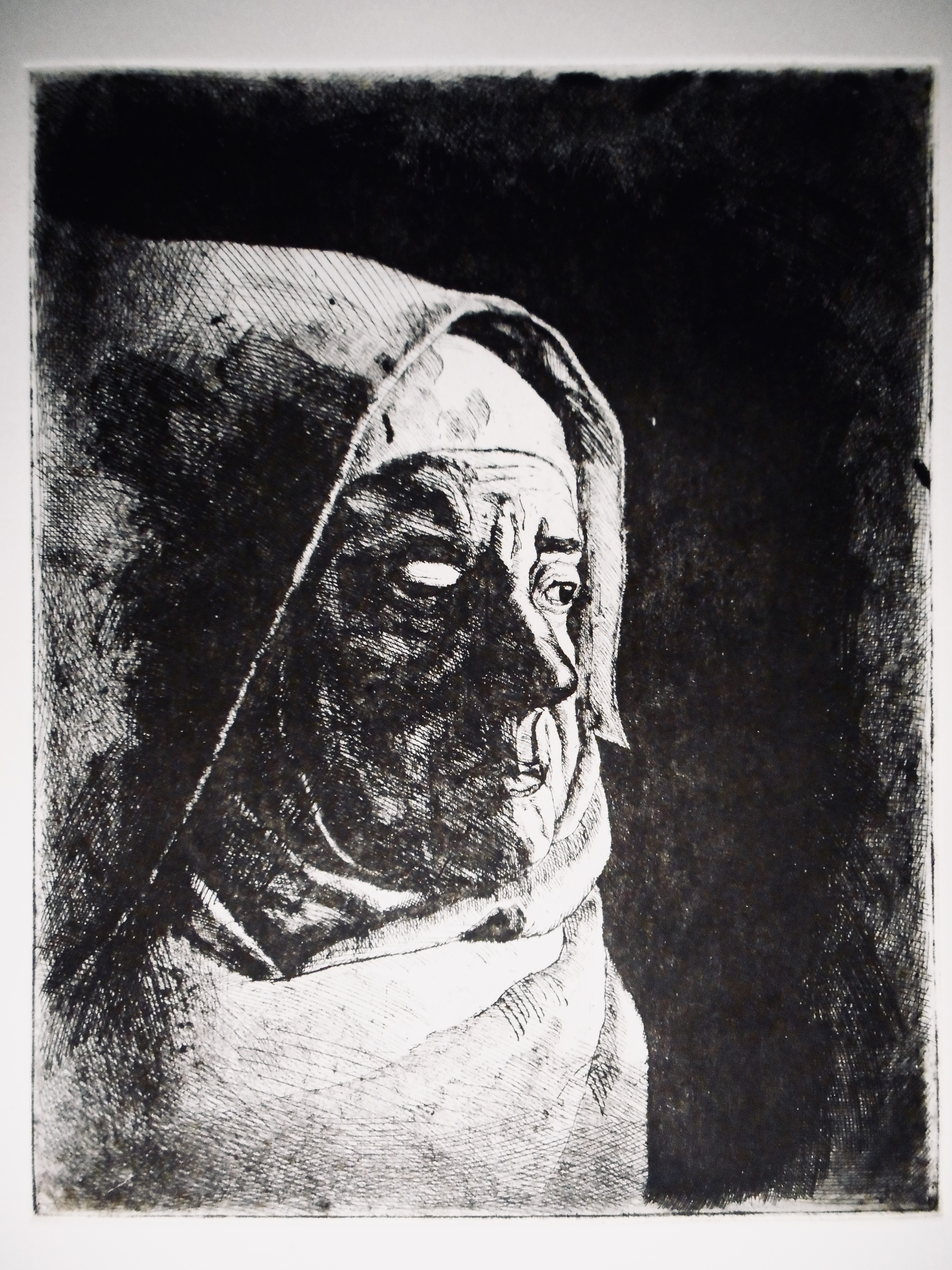 A one-eyed nun in the gloom looks towards the light.