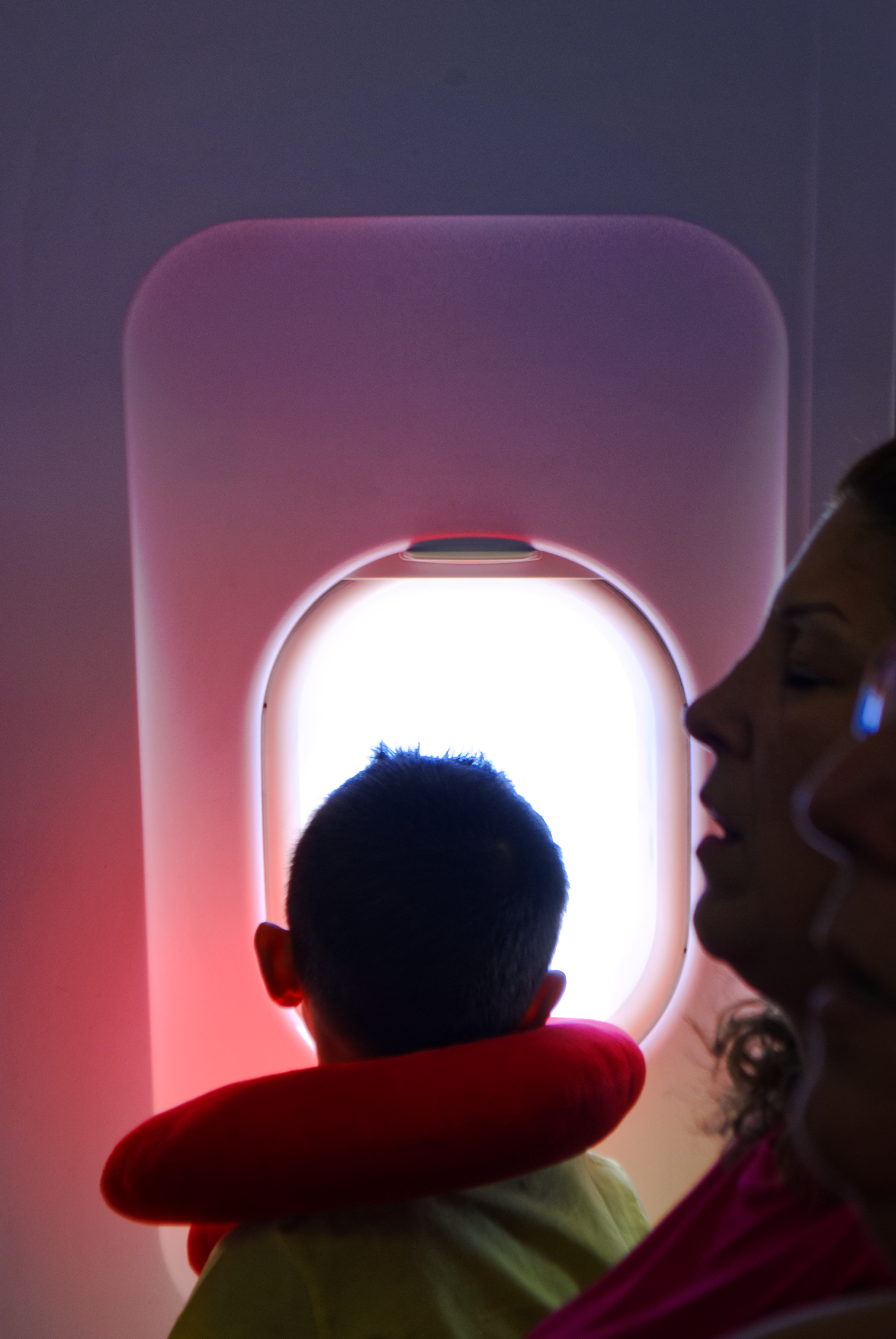 A little boy looking through the window in the airplane