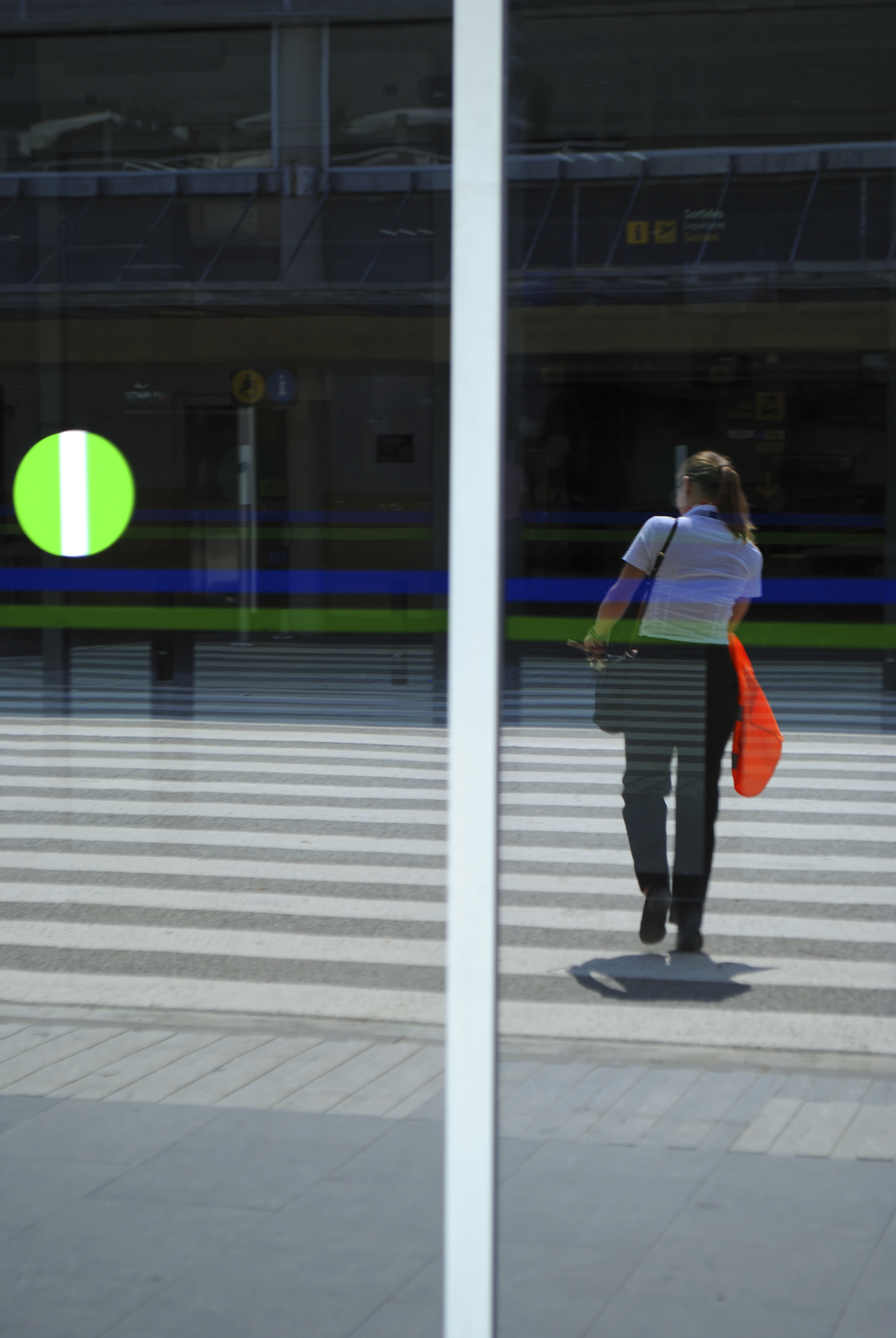 An airport employee crossing the street reflected in the window