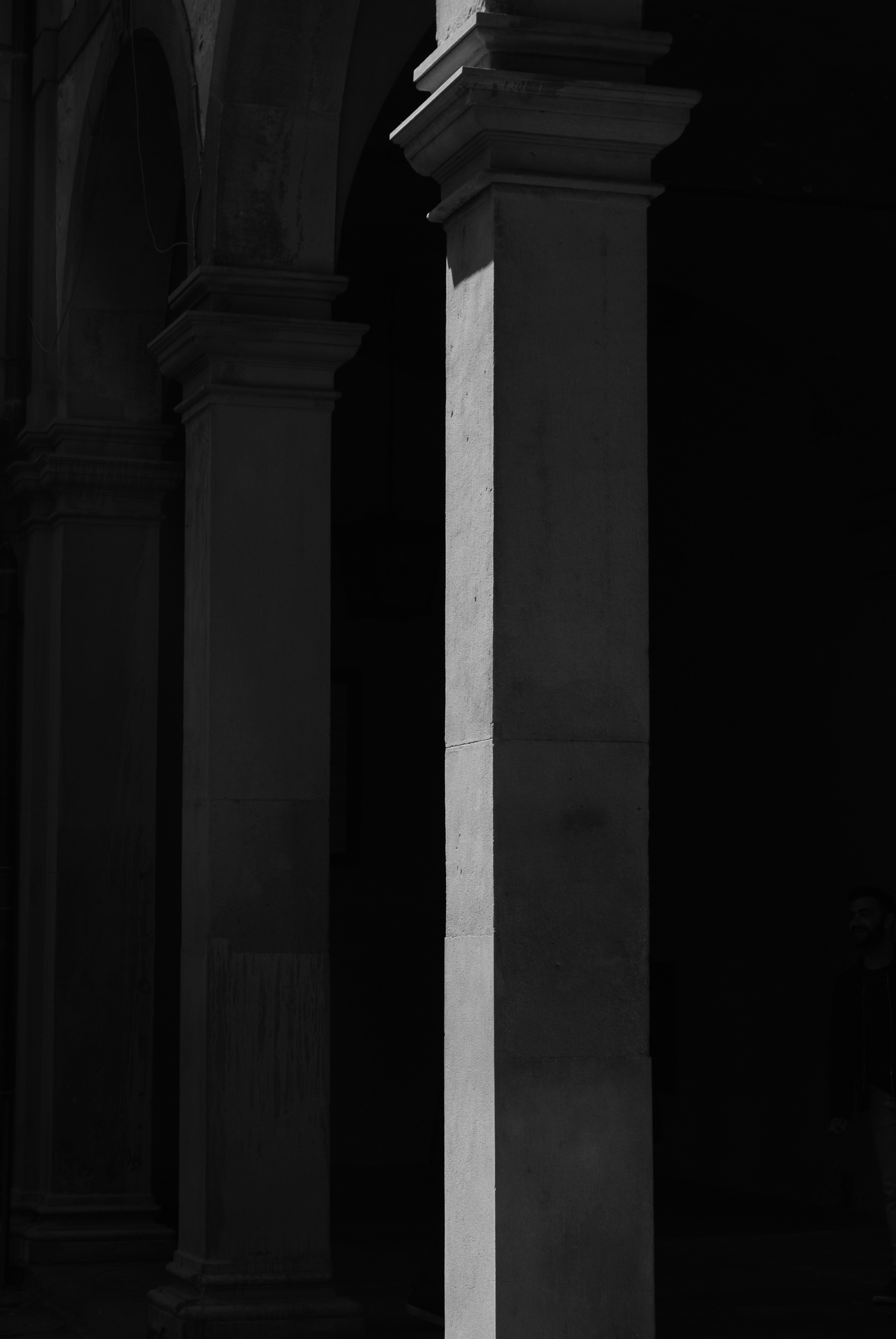 A black and white photograph depicting a classical square column highlighted
