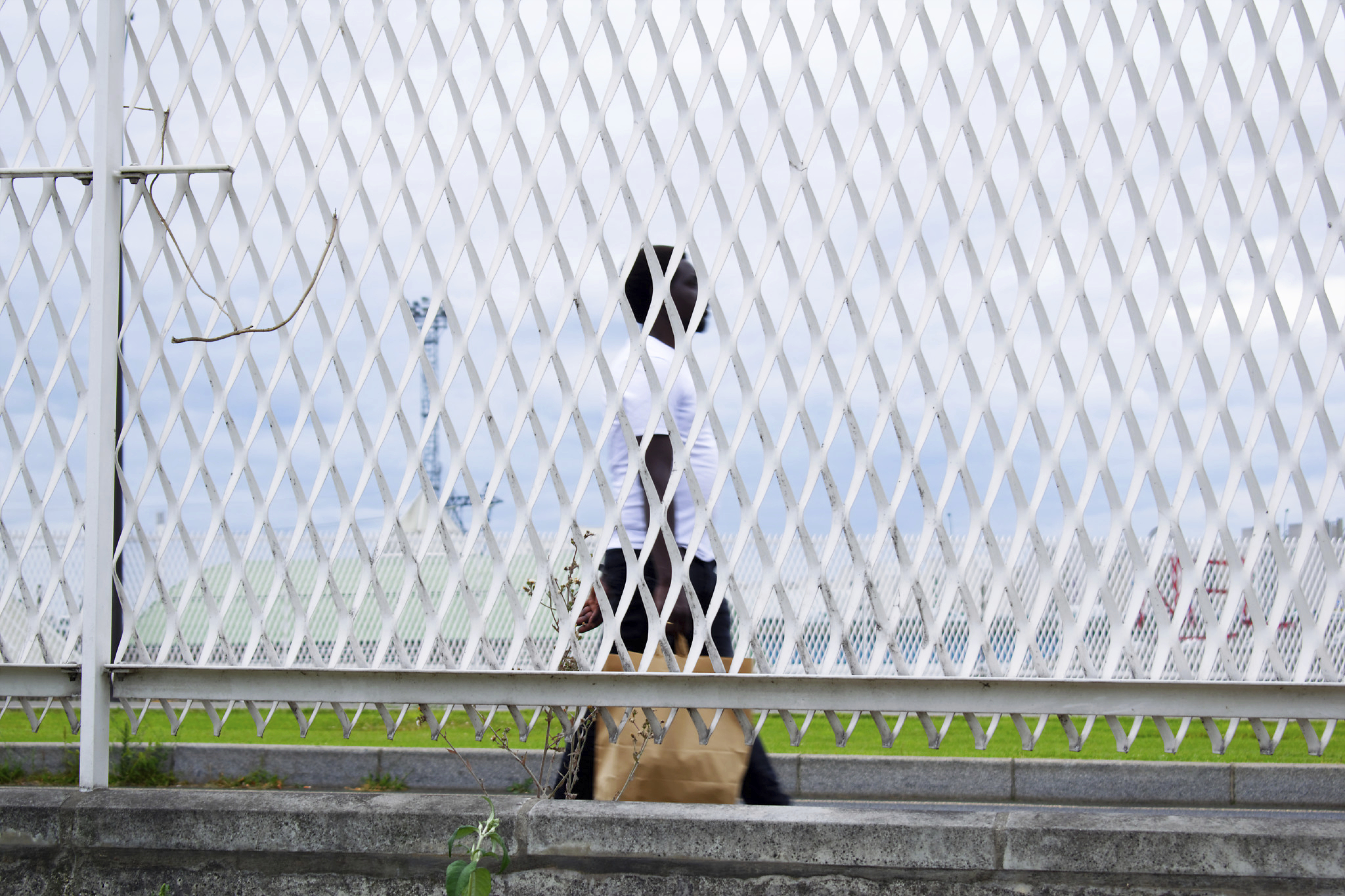 A man walking with shopping bags behind a white fence