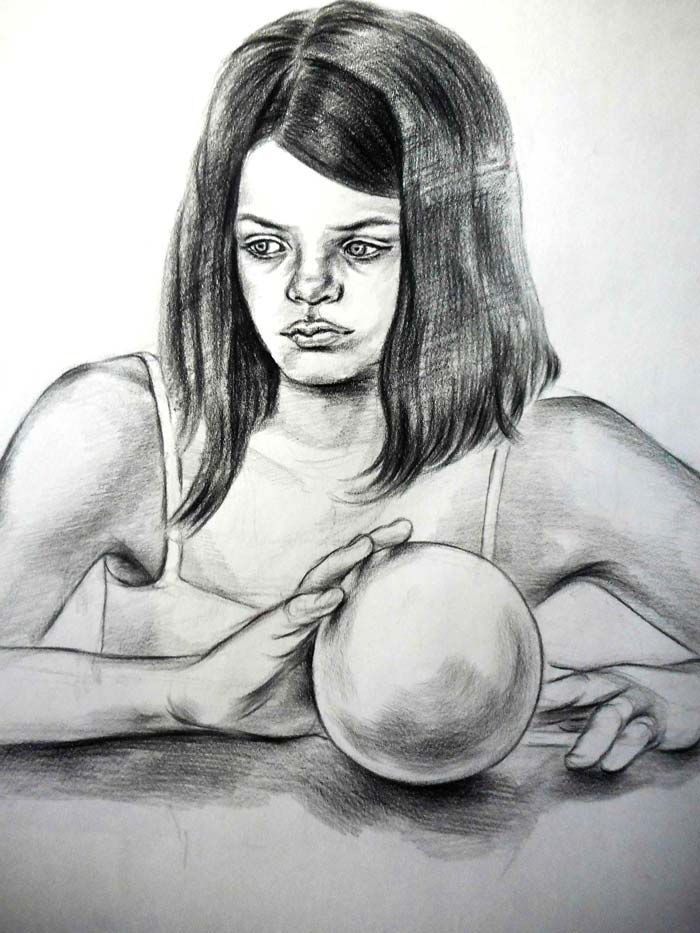  Pensive little girl sitting at the table holding a balloon with her fingers.