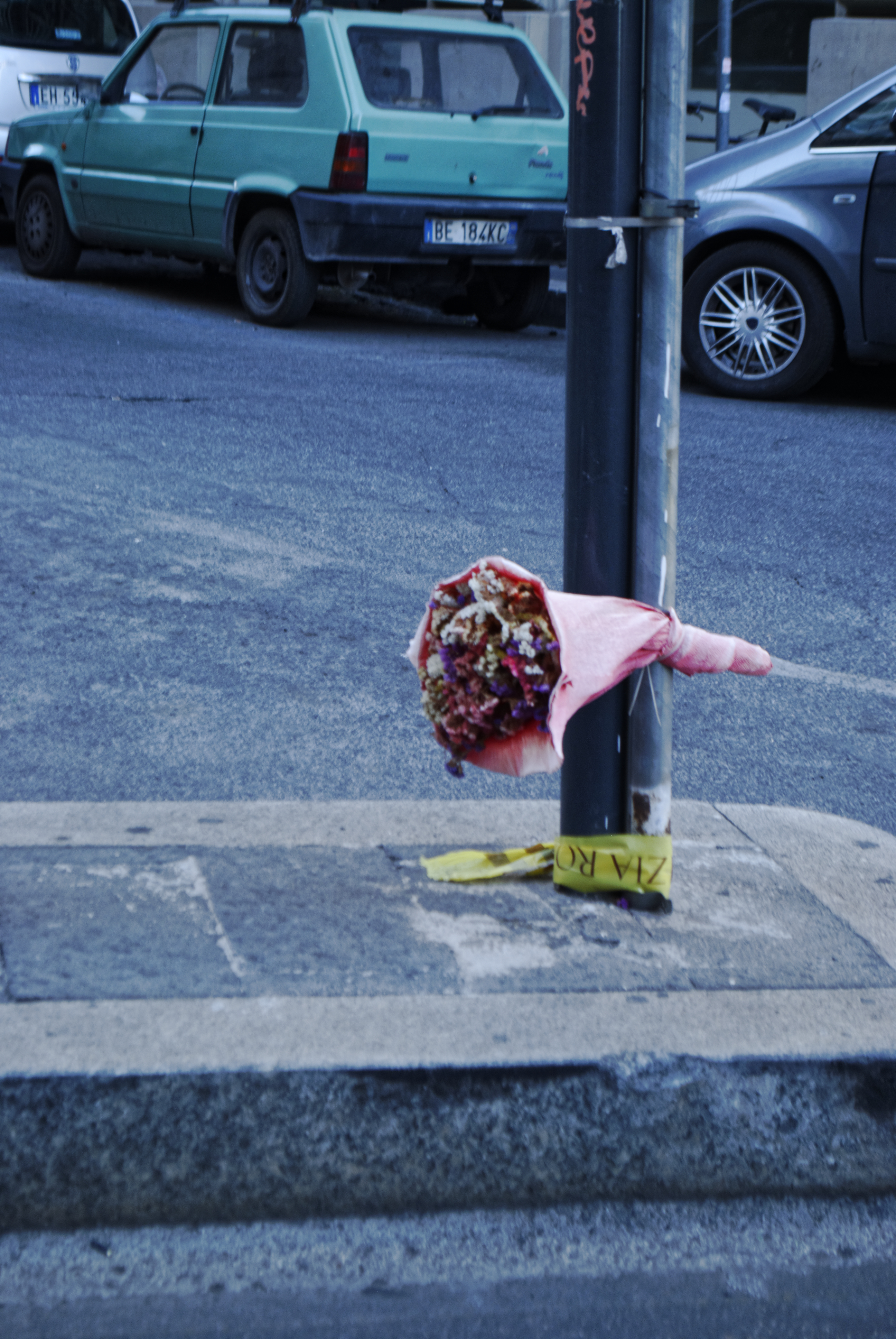 A bouquet of pink flowers hanging on a pole in the street
